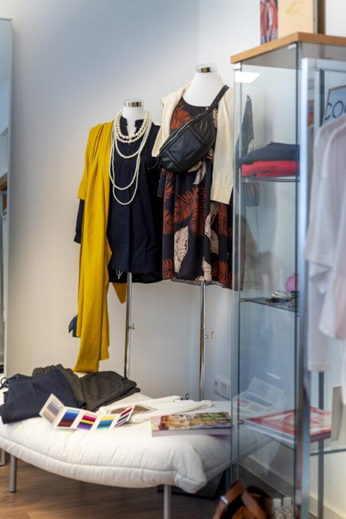 Modische Schaufensterpuppe in einem Bekleidungsgeschäft mit verschiedenen Outfits und Accessoires.