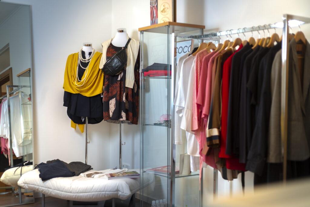 Blick in ein stilvolles Bekleidungsgeschäft mit modischen Outfits auf Schaufensterpuppen und in Regalen.